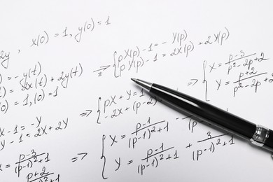 Sheet of paper with mathematical formulas and pen, closeup