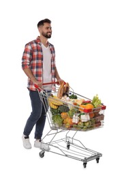 Happy man with shopping cart full of groceries on white background