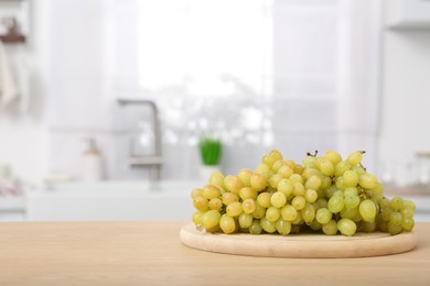 Photo of Fresh ripe grapes on wooden counter in kitchen, space for text