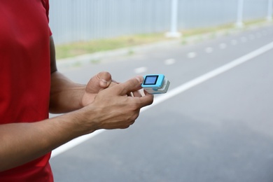 Photo of Young man checking pulse with medical device after training, closeup