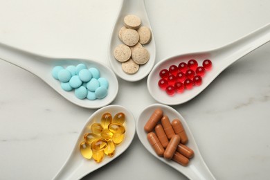 Spoons with different dietary supplements on white table, flat lay