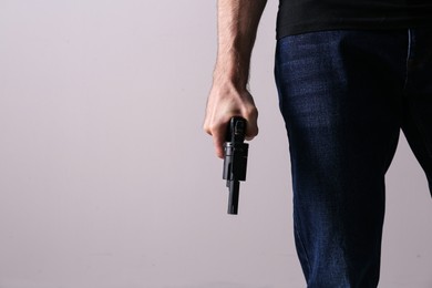 Man holding gun on grey background, closeup. Space for text