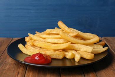 Photo of Tasty french fries served with ketchup on wooden table, closeup