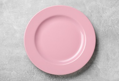 Empty pink ceramic plate on light grey table, top view