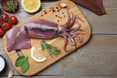 Flat lay composition with fresh raw squid and garnish ingredients on wooden table
