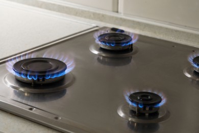 Photo of Gas cooktop with burning blue flames, closeup