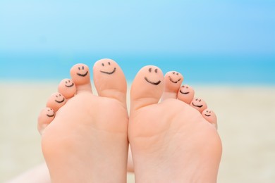 Photo of Woman with smiling faces drawn on toes outdoors, closeup of feet