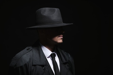 Photo of Old fashioned detective in hat on dark background