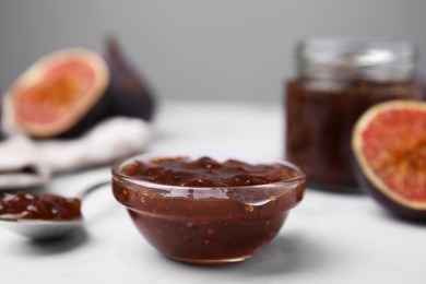 Photo of Tasty sweet fig jam and fruits on white marble table, closeup
