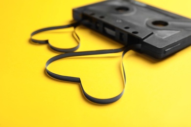 Music cassette and hearts made with tape on yellow background, closeup. Listening love song