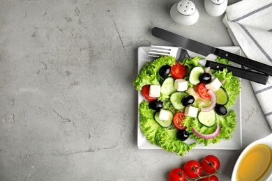 Tasty fresh Greek salad on grey table, flat lay. Space for text