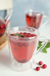 Photo of Tasty hot cranberry tea with mint and fresh berries on light table