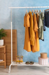 Photo of Rack with stylish clothes near light blue wall indoors