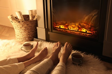 Couple resting near fireplace at home, closeup of legs