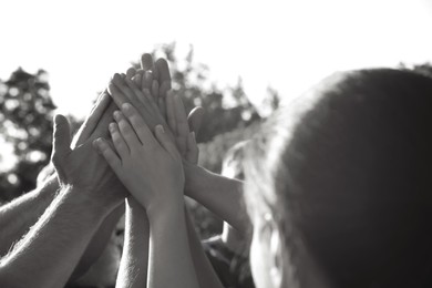 Group of volunteers joining hands together outdoors. Black and white effect