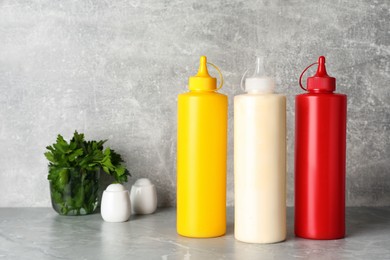 Bottles of mustard, ketchup and mayonnaise on light grey table