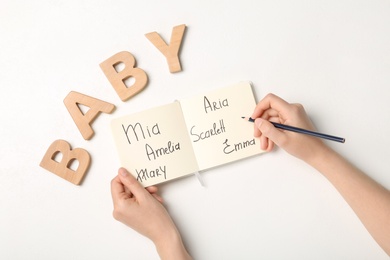 Woman choosing baby name at white table, top view