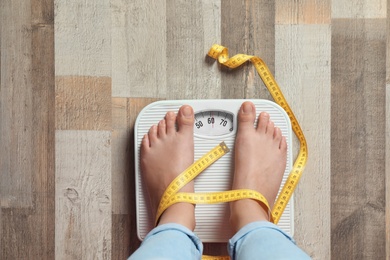 Woman with tied legs measuring her weight using scales on floor. Healthy diet