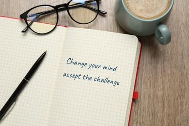 Motivational quote Change Your Mind Accept The Challenge written in notebook, eyeglasses and cup of coffee on wooden table, flat lay