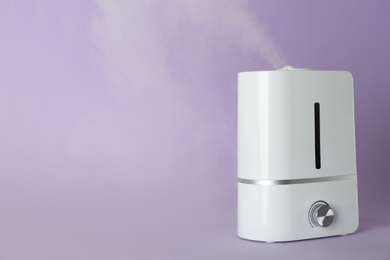 Modern air humidifier on violet background. Space for text
