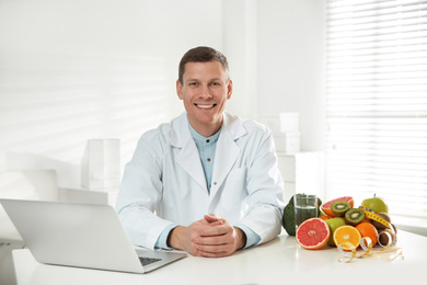 Nutritionist with laptop at desk in office