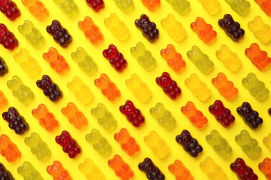 Delicious gummy bear candies on yellow background, flat lay