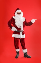 Full length portrait of Santa Claus with sunglasses on red background
