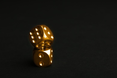 Stacked gold dices on black background. Space for text