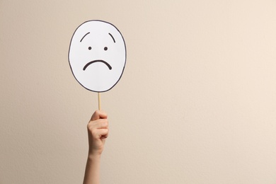 Woman with sad paper face on beige background, closeup. Space for text