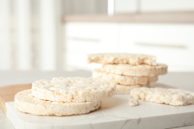 Puffed rice cakes on board indoors, closeup. Space for text