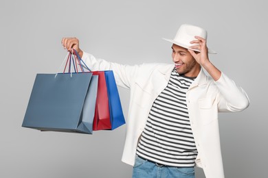Photo of Happy African American man in hat with shopping bags on light grey background