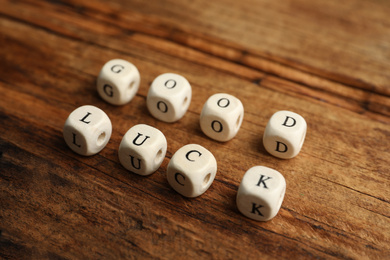 Cubes with phrase GOOD LUCK on wooden table, closeup