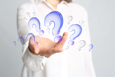 Businesswoman on blue background demonstrating drawings of question mark