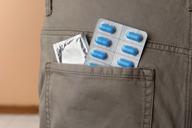 Pants with pills and condom in pocket, closeup. Potency problem