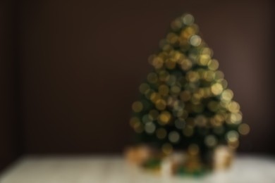 Blurred view of beautifully decorated Christmas tree near brown wall indoors, space for text