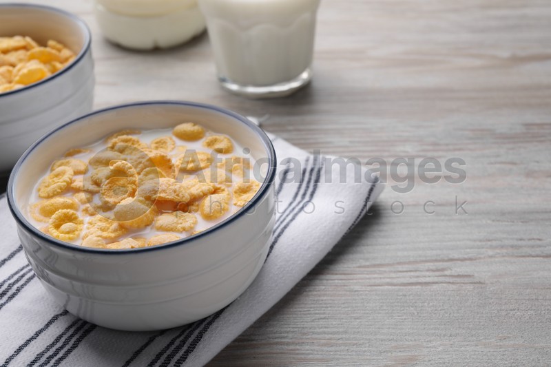 Tasty cornflakes with milk served on wooden table, space for text
