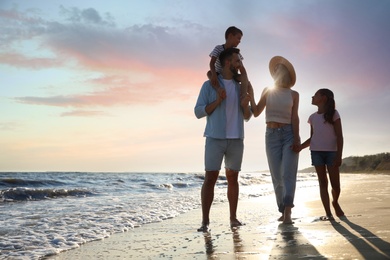 Photo of Happy family walking on sandy beach near sea