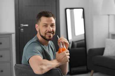 Man holding bottle of delicious juice at home, space for text