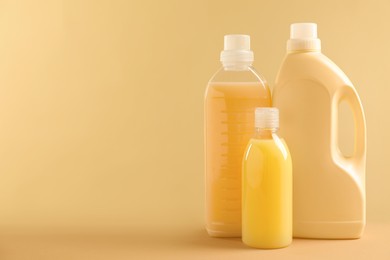 Different bottles with detergents on beige background, space for text
