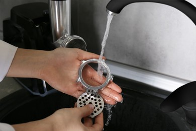 Woman washing parts of electric meat grinder under tap water in kitchen sink indoors, closeup