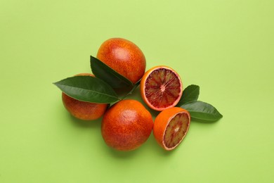 Ripe sicilian oranges and leaves on light green background, flat lay