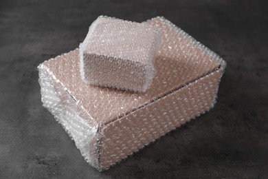 Cardboard boxes covered with bubble wrap on dark grey table