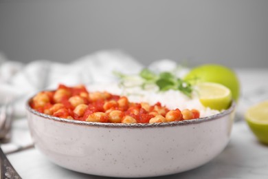 Delicious chickpea curry with rice in bowl on white marble table, closeup