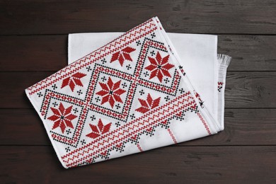 Photo of Beautiful rushnyk on wooden table, top view. Ukrainian national embroidery