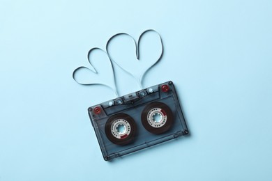 Music cassette and hearts made with tape on light blue background, top view. Listening love song