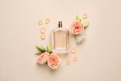 Flat lay composition with bottle of perfume and fresh flowers on beige background