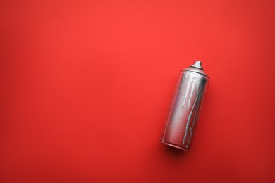 Used can of spray paint on red background, top view with space for text. Graffiti supply