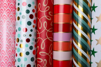 Different colorful wrapping paper rolls as background, top view
