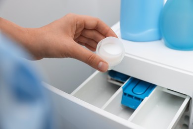 Photo of Woman pouring laundry detergent into drawer of washing machine, closeup