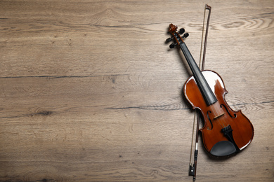 Classic violin and bow on wooden background, top view. Space for text